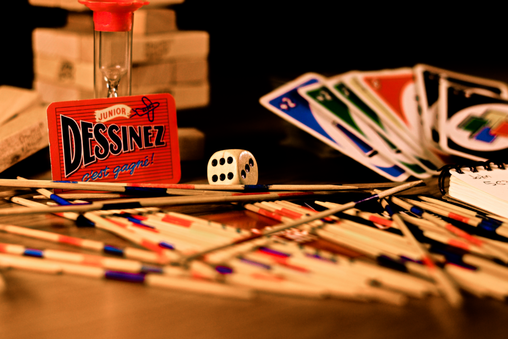 Top jeux de société à découvrir au Baraddur à Bastogne A vibrant arrangement of games, including cards, dice, and sticks, on a table.